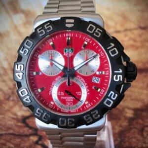 TAG HEUER FORMULA 1, PROFESSIONAL 200M - TEMPPUS: El TAG Heuer Formula 1 con esfera roja es un reloj de diseño deportivo inspirado en el mundo del automovilismo. Pertenece a la icónica colección Formula 1 de la marca, reconocida por sus relojes robustos y funcionales. Este modelo incluye una caja de acero inoxidable de 43 mm de diámetro, y un cristal de zafiro resistente a los arañazos, lo que le otorga durabilidad y una excelente legibilidad. El reloj cuenta con un movimiento de cuarzo, y sus funciones incluyen cronógrafo, horas, minutos, segundos y una ventana para la fecha. La característica esfera roja satinada con efecto “rayos de sol” añade un toque vibrante y dinámico al diseño, mientras que los índices y las manecillas están recubiertos de Super-LumiNova para garantizar la visibilidad en condiciones de poca luz.