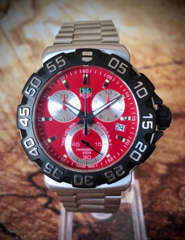 TAG HEUER FORMULA 1, PROFESSIONAL 200M - TEMPPUS: El TAG Heuer Formula 1 con esfera roja es un reloj de diseño deportivo inspirado en el mundo del automovilismo. Pertenece a la icónica colección Formula 1 de la marca, reconocida por sus relojes robustos y funcionales. Este modelo incluye una caja de acero inoxidable de 43 mm de diámetro, y un cristal de zafiro resistente a los arañazos, lo que le otorga durabilidad y una excelente legibilidad. El reloj cuenta con un movimiento de cuarzo, y sus funciones incluyen cronógrafo, horas, minutos, segundos y una ventana para la fecha. La característica esfera roja satinada con efecto “rayos de sol” añade un toque vibrante y dinámico al diseño, mientras que los índices y las manecillas están recubiertos de Super-LumiNova para garantizar la visibilidad en condiciones de poca luz.