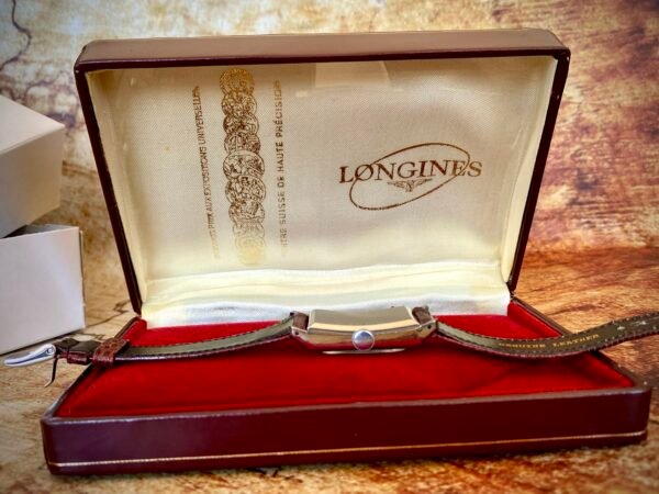 LONGINES ART DECÓ PLATA MACIZA, AÑOS 40 - TEMPPUS: Historia de Longines: 190 Años de Precisión y Elegancia Suiza Longines, una de las marcas relojeras más emblemáticas del mundo, tiene su origen en 1832 en Saint-Imier, Suiza, cuando Auguste Agassiz estableció un taller relojero junto a dos socios bajo el nombre Agassiz & Compagnie. Inicialmente especializados en relojes de bolsillo, ganaron reconocimiento por su precisión milimétrica y acabados artesanales, estableciendo los cimientos de una tradición horológica que perdura hasta hoy. Nacimiento de la marca Longines En 1867, bajo la dirección del sobrino de Agassiz, Ernest Francillon, la compañía experimentó una transformación decisiva. Se construyó la primera fábrica integrada en la zona conocida como Les Longines («los prados largos»), nombre que adoptaría oficialmente la marca. Ese mismo año presentó el revolucionario calibre 20A, su primer movimiento propio, que eliminó la dependencia de subcontratistas gracias a su mecanismo de carga por corona con áncora y escape de palanca. Este hito tecnológico fue galardonado con la medalla de oro en la Exposición Universal de París (1867), consolidando a Longines como sinónimo de innovación suiza. Reconocimiento global y cronometraje deportivo La expansión internacional de Longines se aceleró con logros fundamentales. En 1880 patentó el primer cronógrafo mecánico (calibre 20H), utilizado en competiciones hípicas. Nueve años después registró su emblemático logotipo del reloj de arena alado, convirtiéndose en la marca relojera con la marca registrada más antigua aún activa. El año 1912 marcó otro hito al convertirse en pionera del cronometraje deportivo moderno, cronometrando electrónicamente la Federación Gimnástica Suiza en Basilea, lo que le valió el nombramiento como cronometrador oficial de los Juegos Olímpicos desde 1924. Evolución técnica e iconos de diseño Longines fusionó sofisticación mecánica con elegancia atemporal a través de innovaciones clave. En 1927 lanzó el primer reloj antimagnético (calibre 21.59) para científicos, mientras en 1945 presentó su primer movimiento automático, el calibre 22A, dentro de la colección Elegance. La década de 1950 vio nacer el Conquest, su primera línea resistente al agua con sellado reforzado, símbolo de robustez. Ya en el siglo XXI, relanzó la Master Collection con complicaciones avanzadas como fases lunares y GMT, e introdujo el buceador profesional HydroConquest con 300 metros de resistencia. Legado actual: tradición y tecnología Hoy, Longines mantiene su manufactura original en Saint-Imier, donde produce más de 1.5 millones de relojes anuales. Combina movimientos propios de alta eficiencia como el L888 (72 horas de reserva de marcha) con colecciones que rinden homenaje a su herencia, como la Flagship Heritage (reedición del modelo de 1957) y la línea Spirit inspirada en la aviación. Su compromiso con el deporte perdura como cronometrador oficial de la Federación Ecuestre Internacional, el Abierto de Francia de Tenis y los Juegos Olímpicos, reafirmando 190 años de excelencia en precisión, innovación y elegancia intemporal. TEMPPUS. Todos los derechos reservados.  