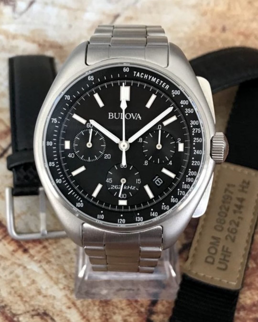 BULOVA LUNAR PILOT "APOLLO 15", NUEVO FULL SET - TEMPPUS: El Bulova Lunar Pilot tiene un lugar especial en la historia de la exploración espacial. Este reloj fue diseñado específicamente para la misión Apolo 15 de la NASA en 1971 y se utilizó como respaldo cuando el Omega Speedmaster del comandante David Scott falló. Este reloj, una pieza única, fue subastado en 2015 por 1.3 millones de dólares debido a su relevancia histórica. En 2015, Bulova lanzó una versión comercial del Lunar Pilot, manteniendo un diseño fiel al original pero incorporando un movimiento cuarzo de alta frecuencia (262 kHz) que garantiza una precisión excepcional (variación de ±10 segundos al año). También se modernizó con un cristal de zafiro plano y mejoras en los materiales, aunque el diseño general conserva su estética retro. Actualmente, es un modelo muy valorado tanto por coleccionistas como por amantes de la relojería TEMPPUS. Todos los derechos reservados.